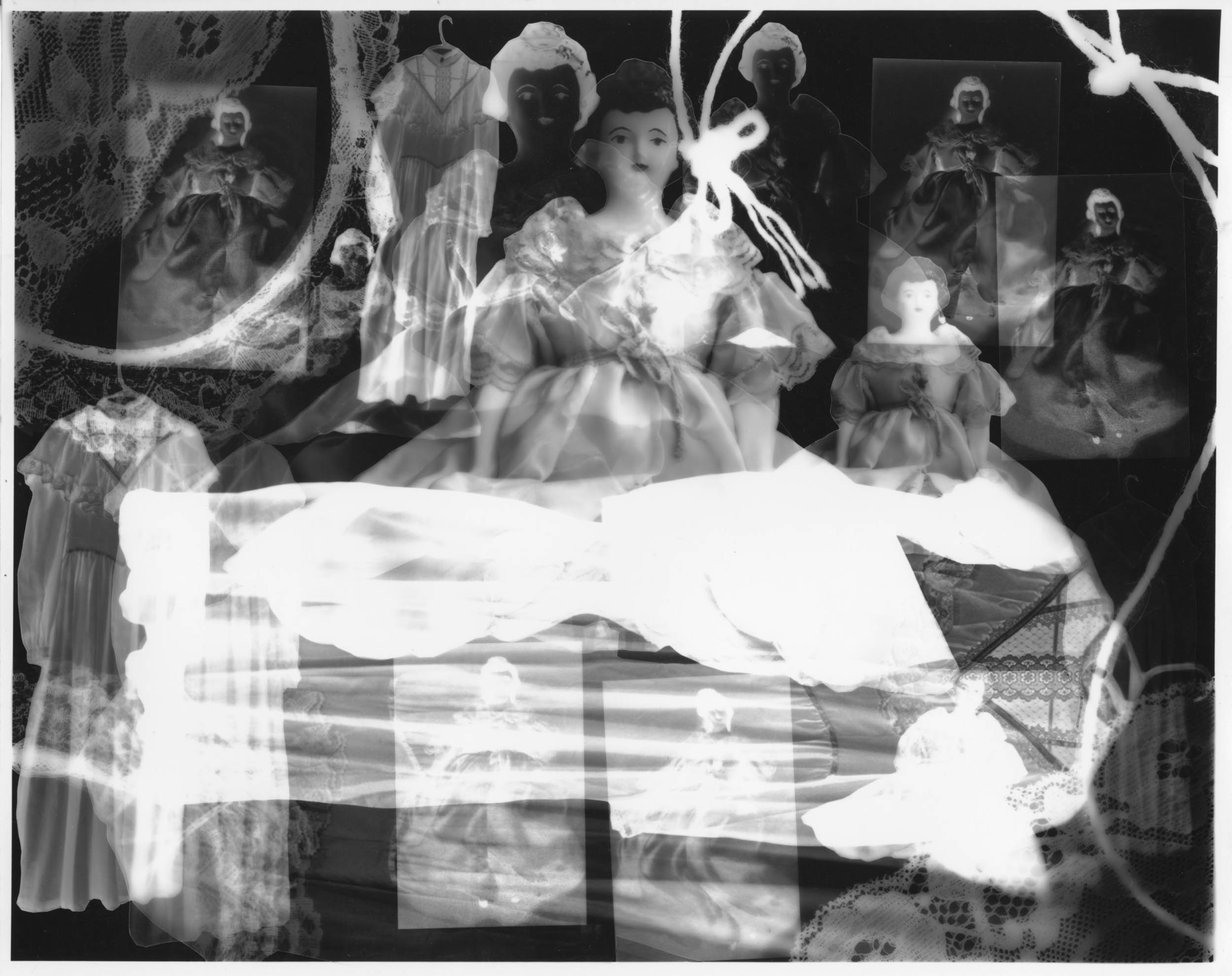 Black and white silver gelatin photogram of multiple transparent images of dolls, both positive and negative, overlapping one another. White silhouettes from lace and thread overlays the dolls.