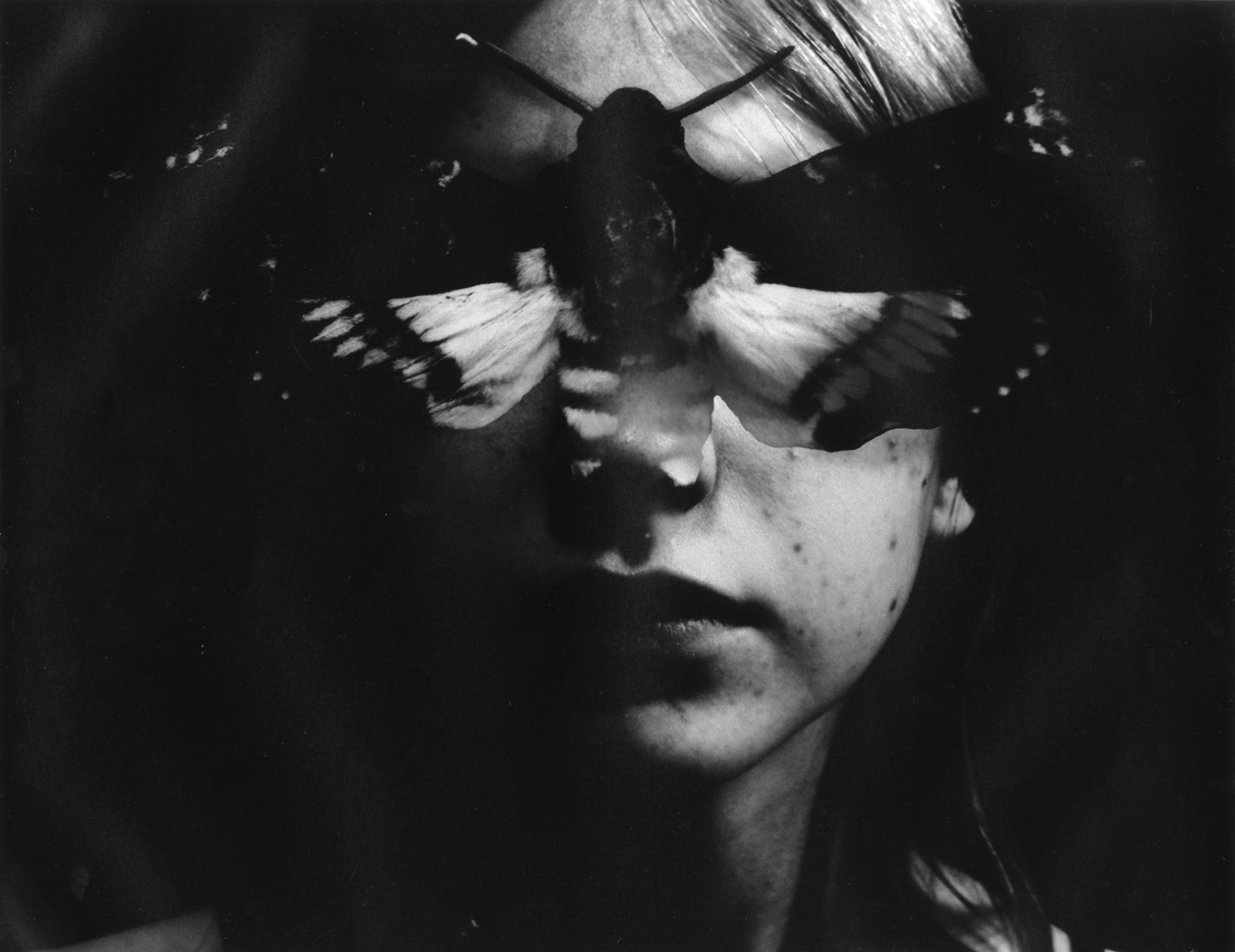 Black and white gelatin silver print of a woman's face with a death's-head moth blocking the eyes