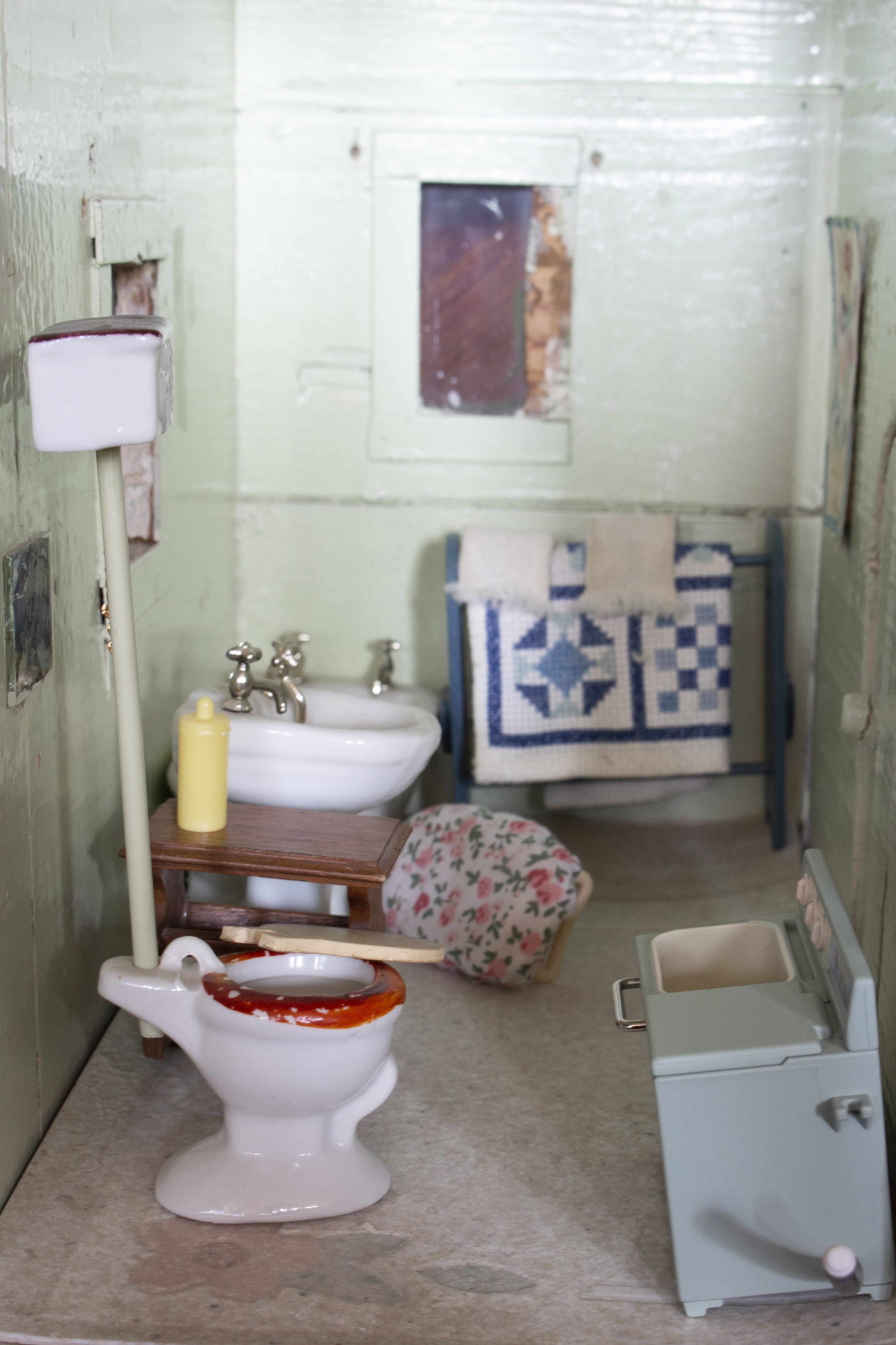 A miniature bathroom with teal-blue walls, a porcelain toilet and sink, and green washing machine.